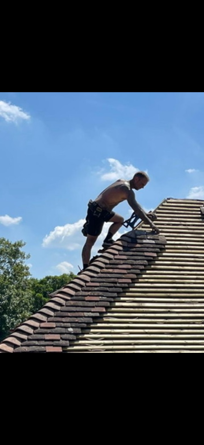 Roofer working high on a tiled roof