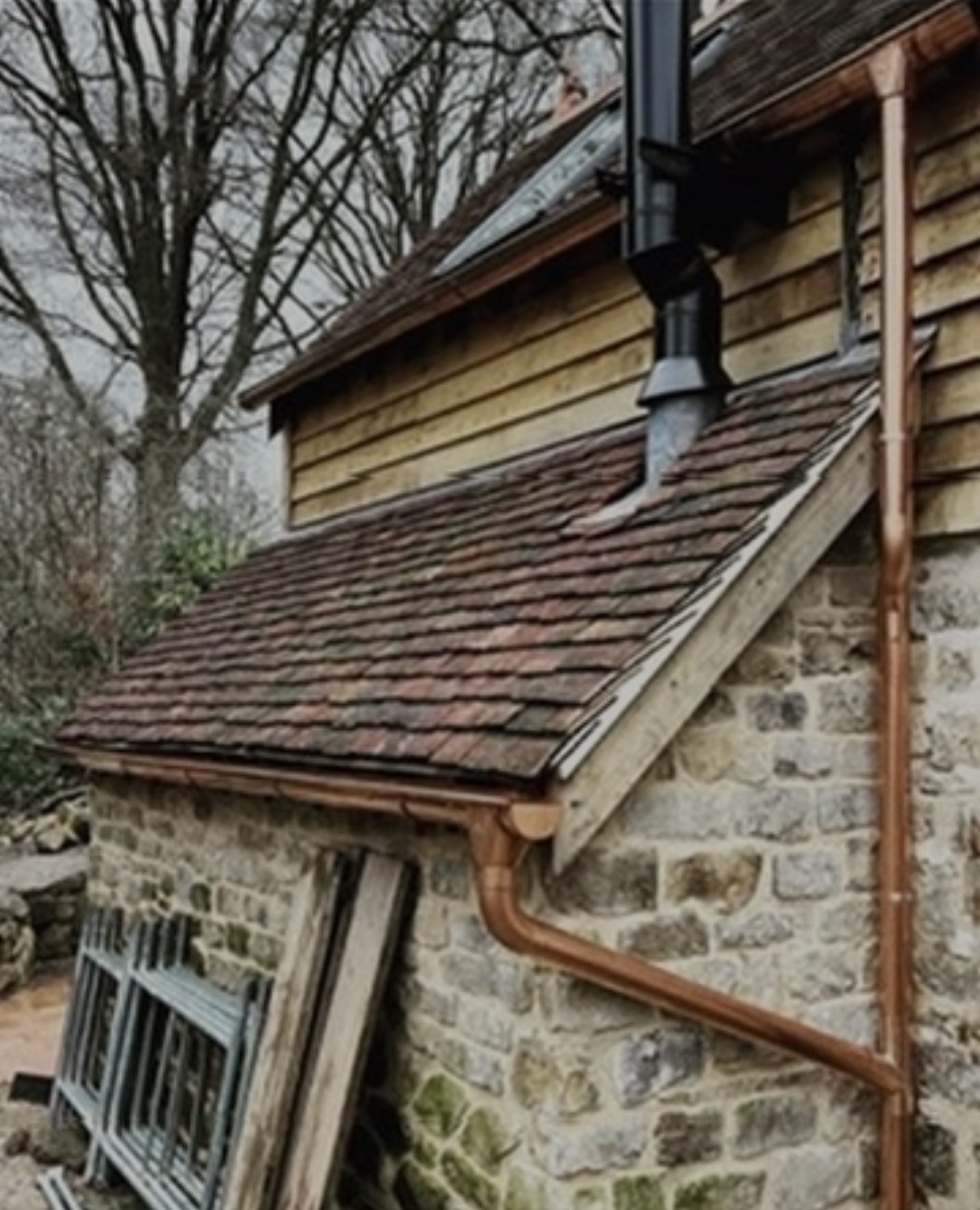 Traditional stone building with tiled roof and copper rainwater goods